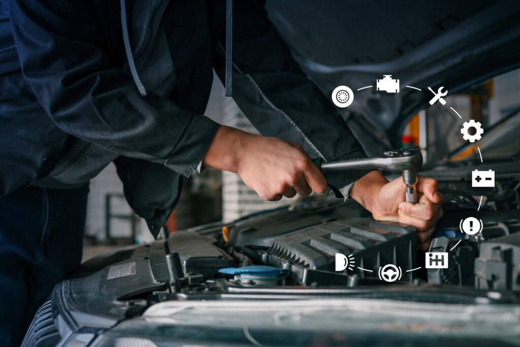 Mechanic using wrench to fix car engine with virtual automotive icons representing various diagnostics and maintenance services displayed around the image
